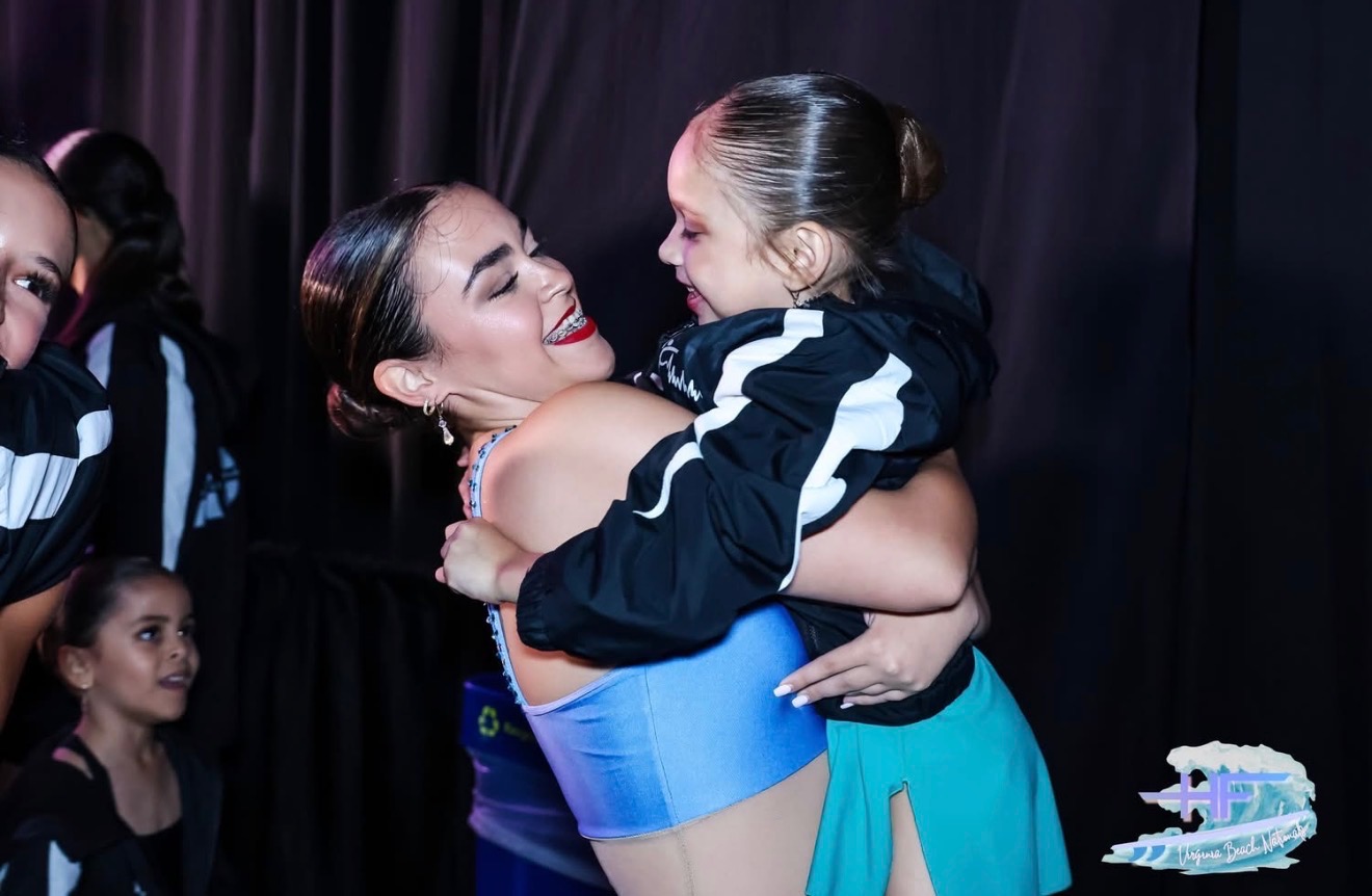 Instructor hugging young dancer backstage